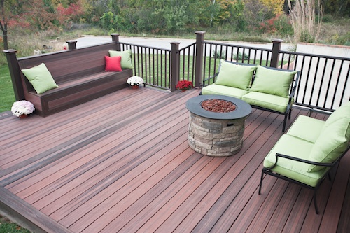 This photo shows the CAMO Hidden Deck Fastening System used with TAMKO EverGrain Envision decking in Shaded Auburn with Rustic Walnut accent and Marquee Railing in Dark Walnut with Weathered Copper accessories.