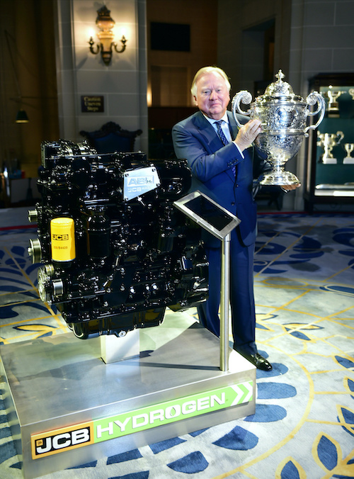 Lord Bamford pictured with the Dewar Trophy and the JCB hydrogen fueled engine being honored with the award.