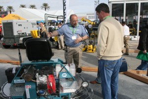 Jeff Durgin (L), president of Bartell Morrison USA, discusses the benefits of his company's proprietary emissions system for ride-on trowels, which burns 92 percent clean to minimize the risk of carbon monoxide hazards, even when used indoors. 